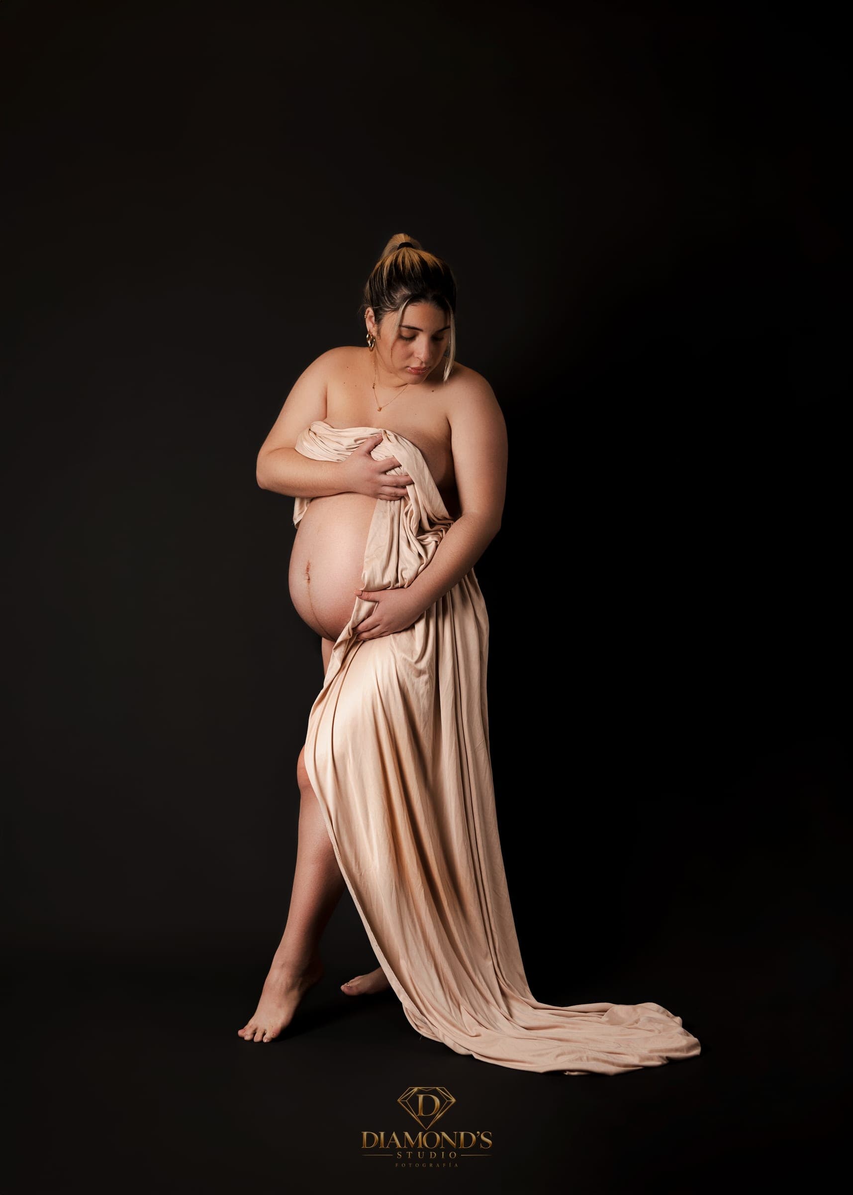 Sesión de maternidad: de pie con tela color champán sobre fondo oscuro