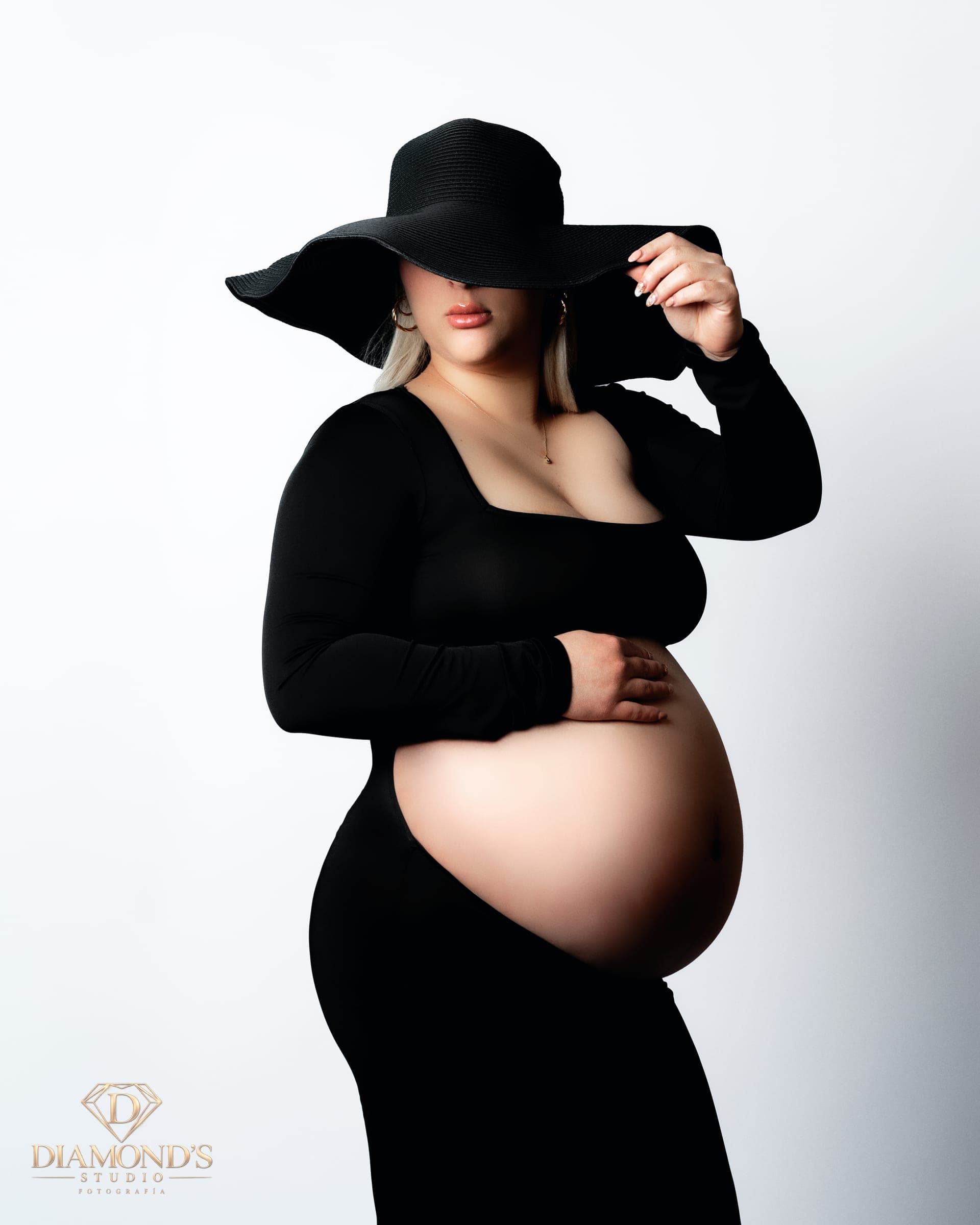 Maternity session: black wide-brim hat with the belly in profile