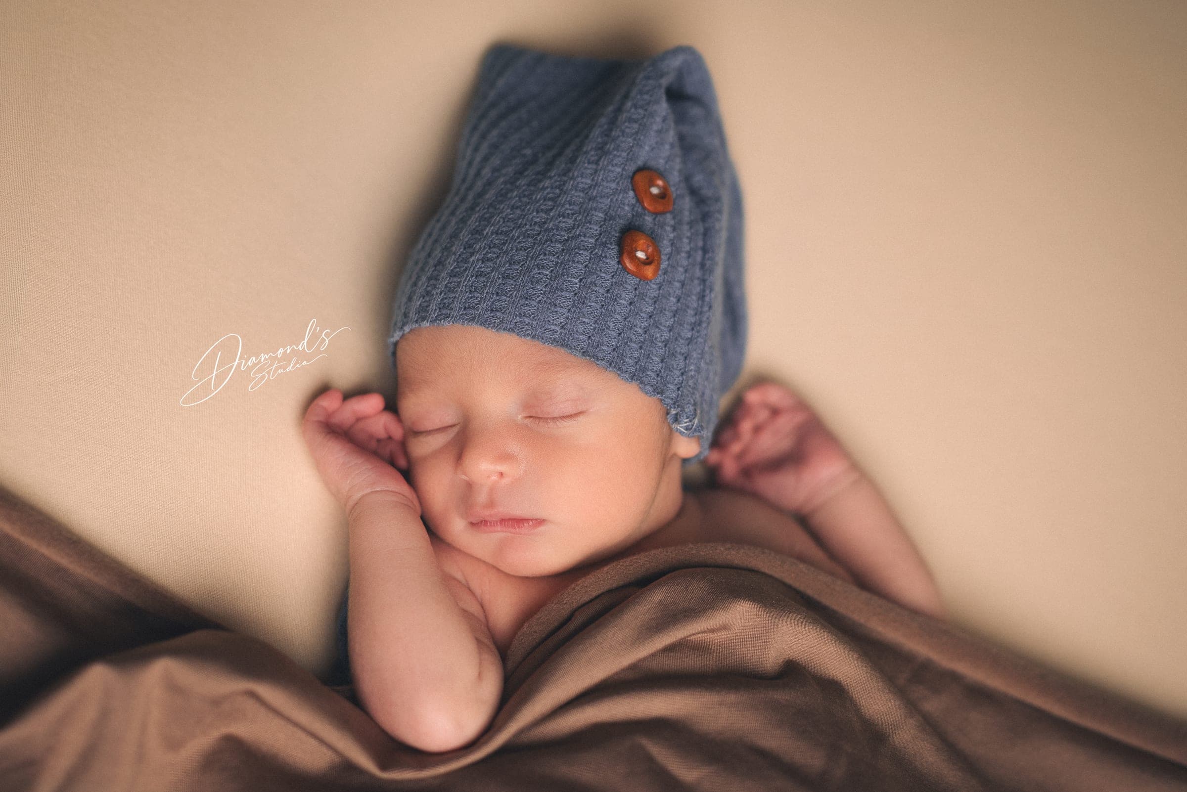 Newborn session: sleeping newborn in a blue knit hat