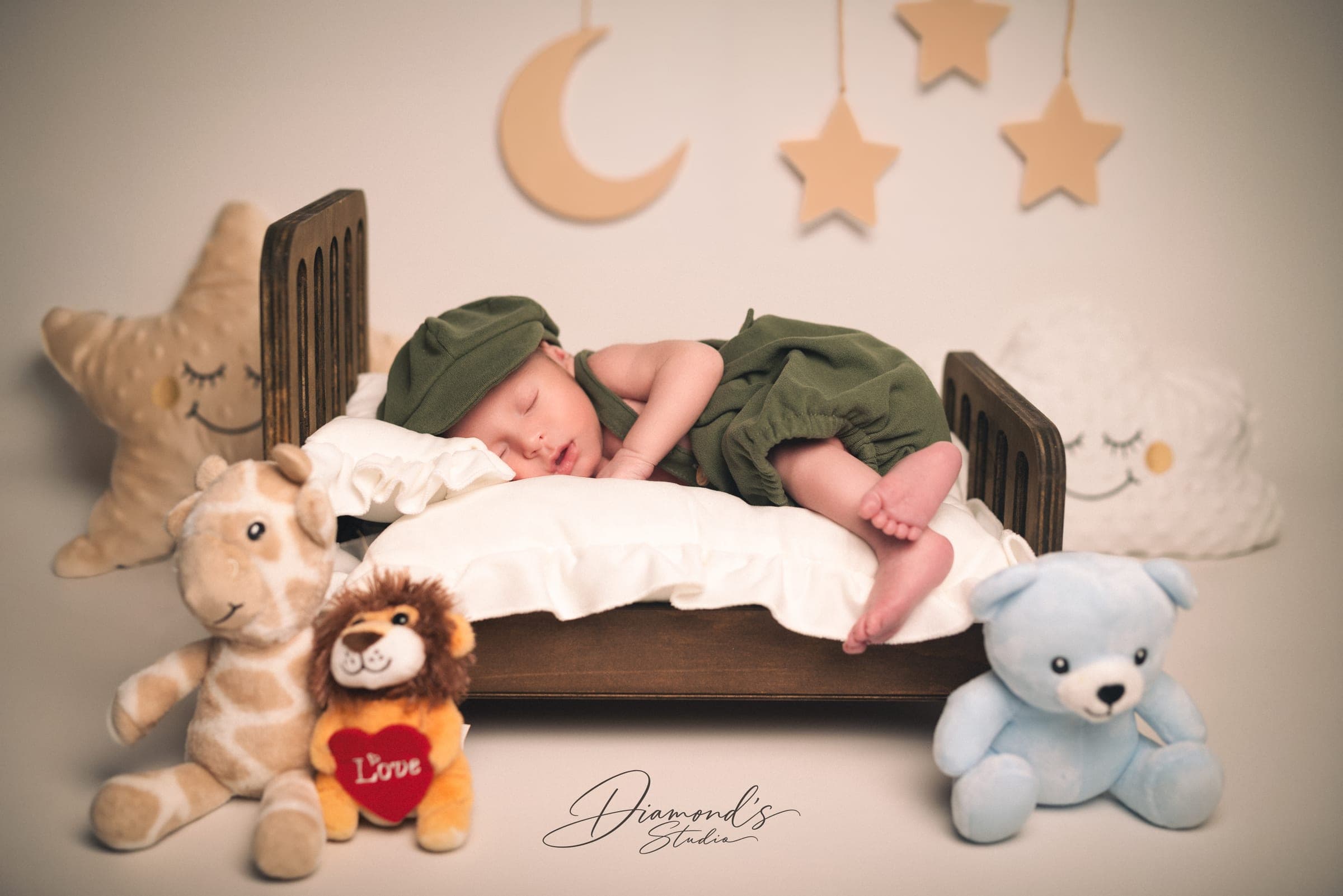 Newborn session: newborn in a little bed with moons, stars and plush toys