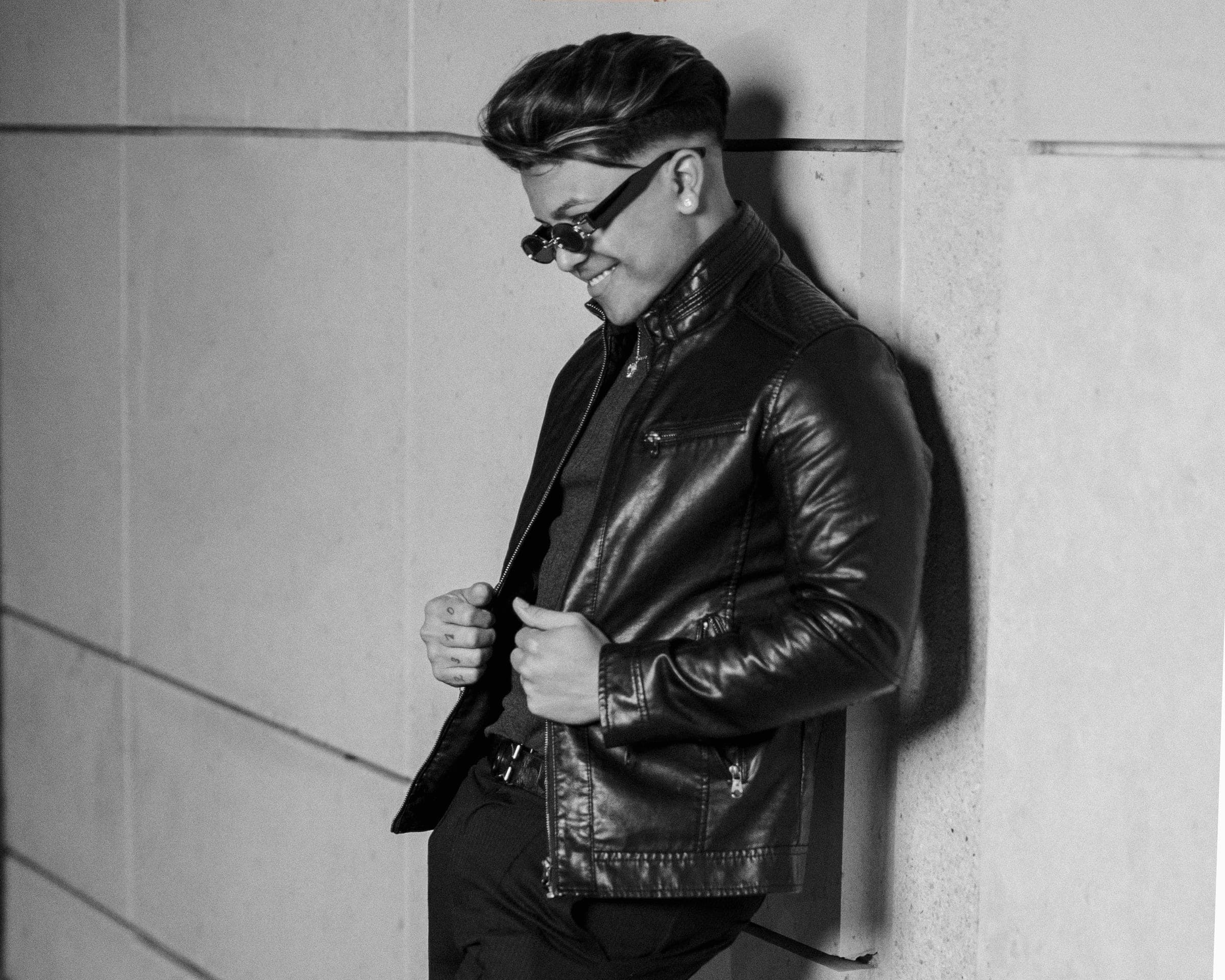 Sesión de retrato: joven con chaqueta de cuero junto a una pared, en blanco y negro